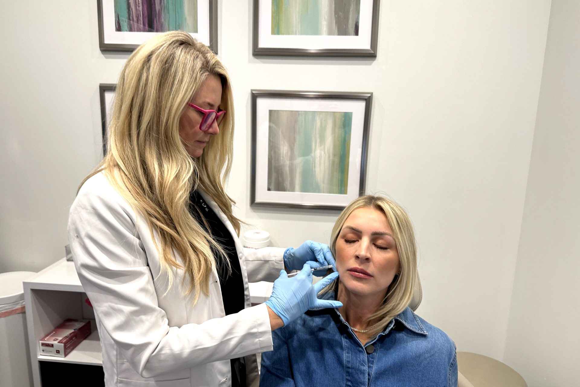 Expert female orthodontic doctor with blonde hair providing compassionate and professional TMJ treatment to a blonde patient, ensuring personalized care and optimal oral health.