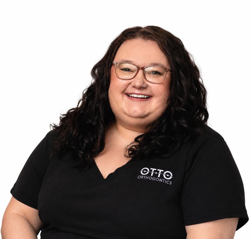 Naomi, Administrative Team member at Otto Orthodontics, smiling in a black Otto Orthodontics scrub top.